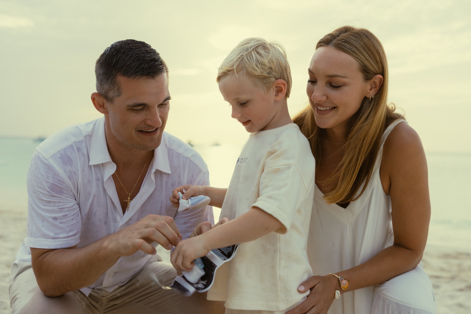 Jonathan and Jaclyn helping their son hold tiny baby shoes and an ultrasound