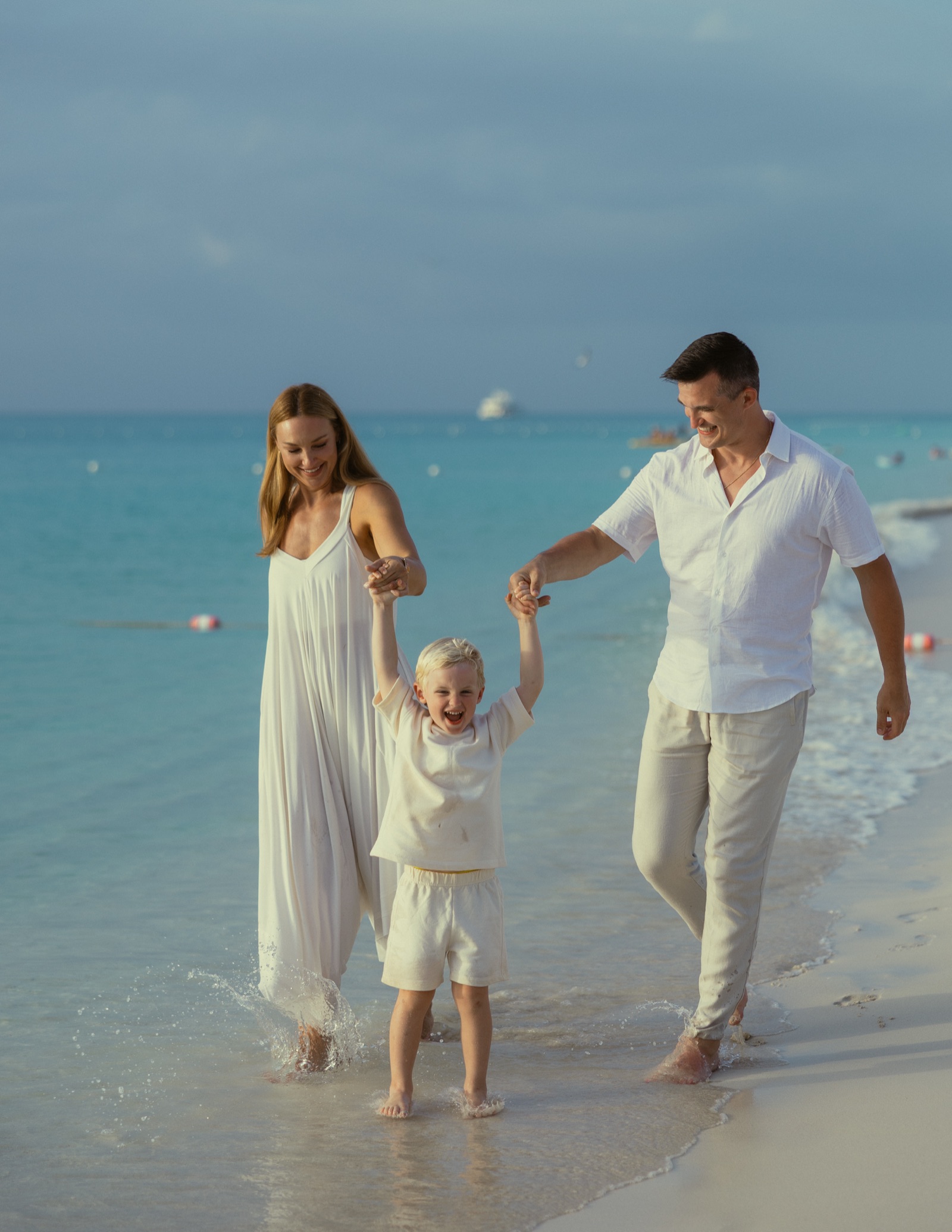 Jonathan, Jaclyn, and their son walking in the surf on a beach