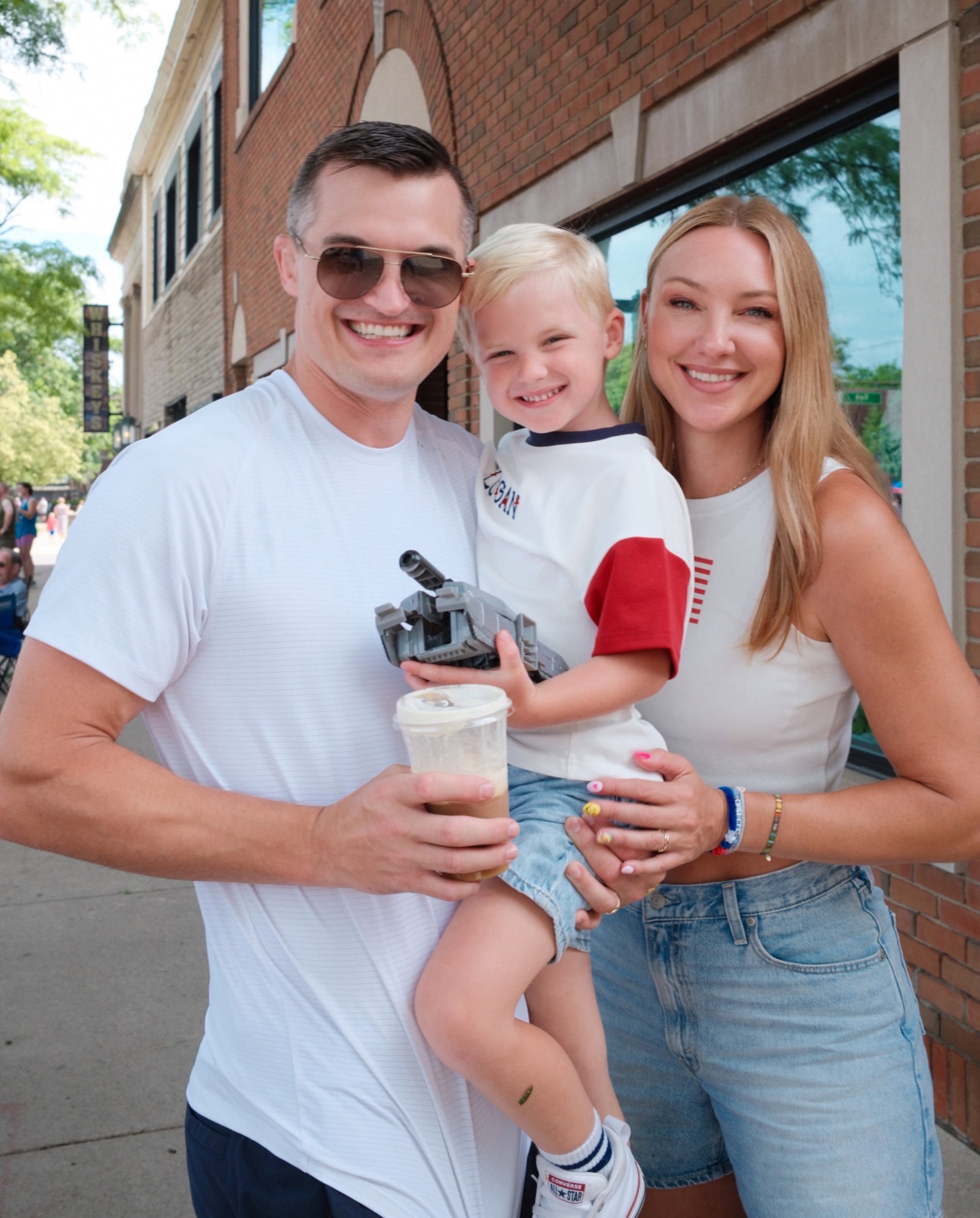 Jonathan, Jaclyn, and their son downtown with a toy tank and an iced coffee